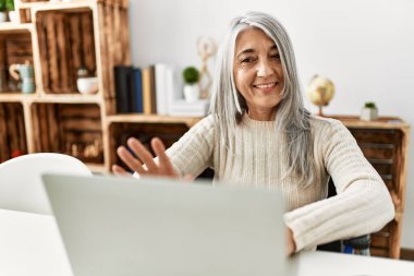 Orta yaşlı, kır saçlı, gülümseyen bir kadın.
