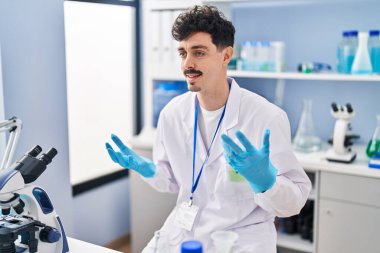 Young caucasian man scientist smiling confident speaking at laboratory