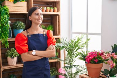 Çiçekçiye kollarını kavuşturup gülümseyen güzel İspanyol kadın.