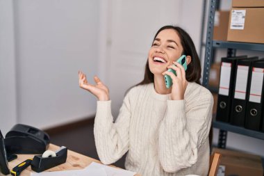 Genç kadın dış ticaret işçisi ofisteki akıllı telefondan konuşuyor.