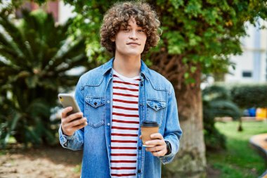 Genç İspanyol adam parkta akıllı telefon kullanıyor.