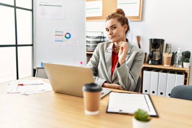 Ofiste çalışan genç bir iş kadını dizüstü bilgisayar kullanıyor.