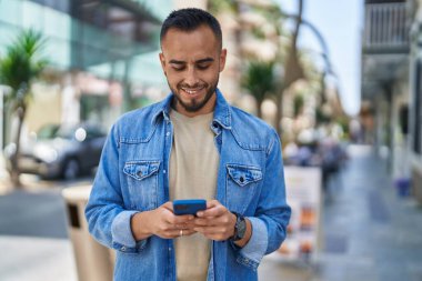 Sokakta akıllı telefon kullanan, kendine güvenen genç bir İspanyol.