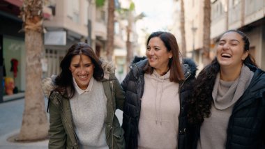 Mother and daugthers smiling confident hugging each other at street