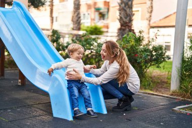 Mother and son playing on slide at park