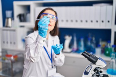 Laboratuvarda elinde haplar tutan orta yaşlı kadın bilim adamı.