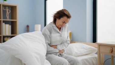 Orta yaşlı İspanyol kadının yatak odasında karnı ağrıyor.