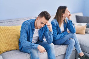Man and woman couple unhappy sitting on sofa at home