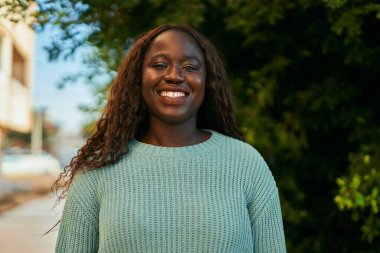 Genç Afrikalı kadın parkta mutlu gülümsüyor.