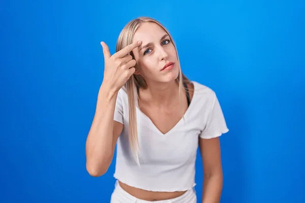 Young Caucasian Woman Standing Blue Background Pointing Unhappy Pimple Forehead — Stockfoto