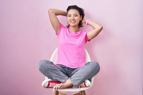 Hispanic Young Woman Sitting Chair Pink Background Relaxing Stretching Arms — Stock Photo, Image