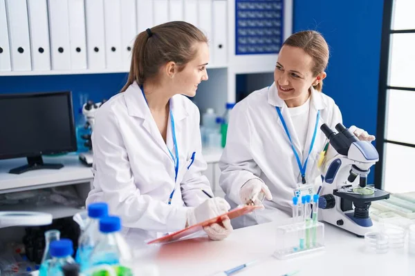 Duas Mulheres Cientistas Usando Microscópio Escrever Documento Laboratório — Fotografia de Stock