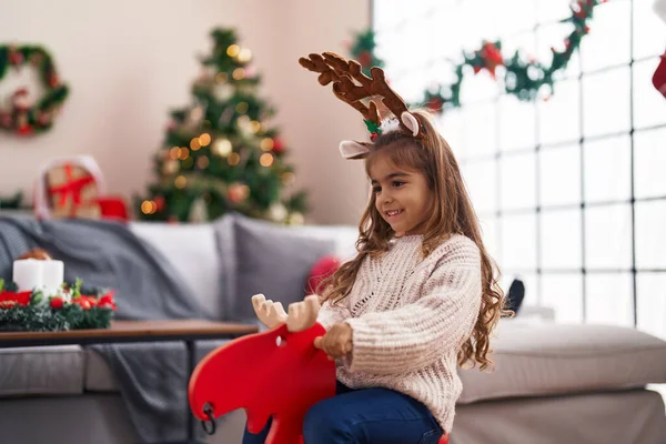 Schattig Latino Meisje Spelen Met Rendier Schommelen Door Kerstboom Thuis — Stockfoto