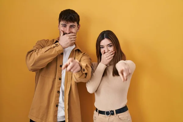 Young Hispanic Couple Standing Yellow Background Laughing You Pointing Finger — Stockfoto