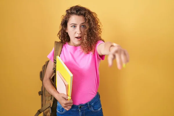 Young Caucasian Woman Wearing Student Backpack Holding Books Pointing Finger — Stok fotoğraf