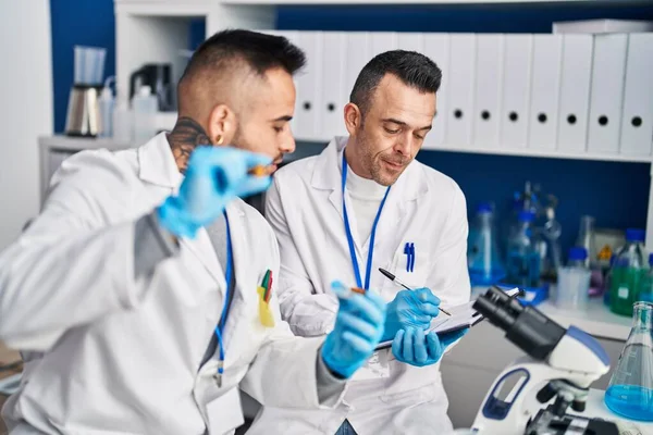 Δύο Άνδρες Επιστήμονας Που Γράφει Έγγραφο Κρατώντας Χάπια Στο Εργαστήριο — Φωτογραφία Αρχείου