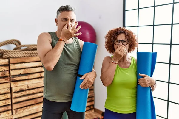 Middle Age Couple Holding Yoga Mat Smelling Something Stinky Disgusting — Stockfoto