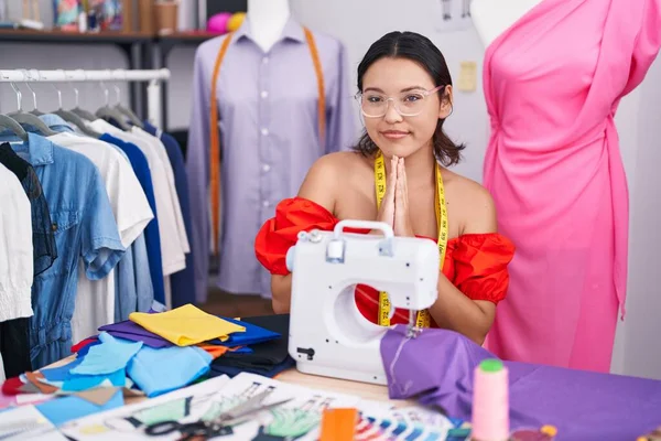 Hispanic Young Woman Dressmaker Designer Using Sewing Machine Praying Hands — Stockfoto