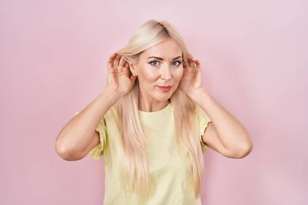 Caucasian Woman Standing Pink Background Trying Hear Both Hands Ear —  Fotos de Stock