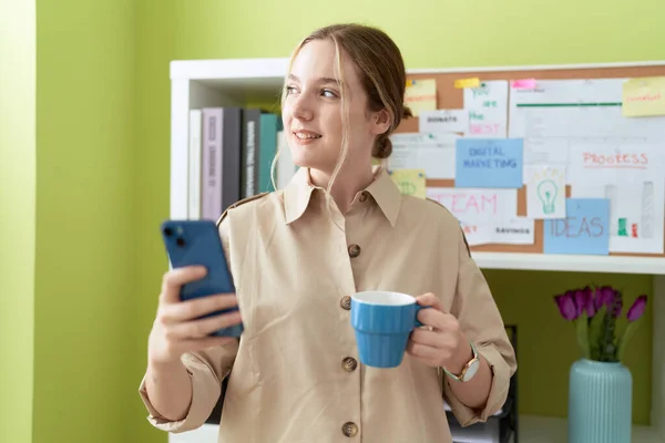 オフィスでスマートフォンのコーヒーを使用して若い白人女性ビジネスワーカー — ストック写真