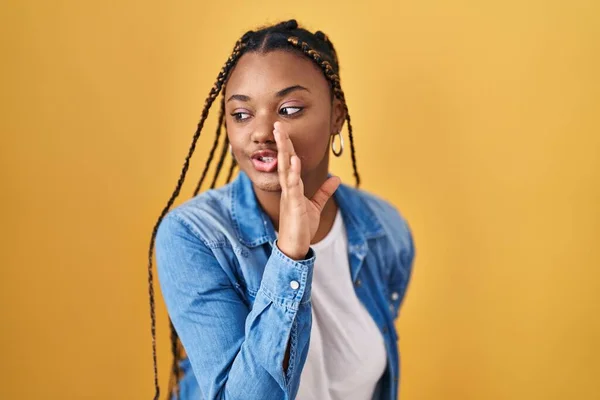 African American Woman Braids Standing Yellow Background Hand Mouth Telling — Stockfoto