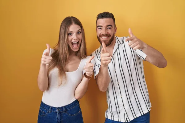 Young Couple Standing Yellow Background Pointing Fingers Camera Happy Funny — Stockfoto