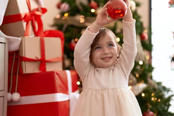 Adorable Girl Holding Ball Decoration Standing Christmas Tree Home — Stock Photo, Image