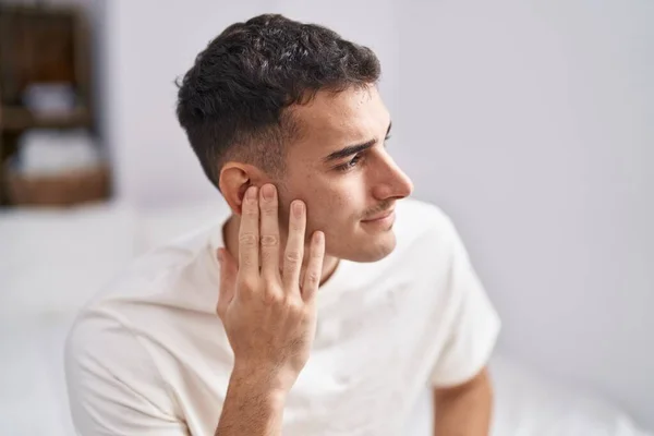 Young Hispanic Man Suffering Ear Pain Sitting Bed Bedroom — Zdjęcie stockowe