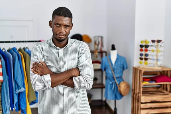 Young african american man working as manager at retail boutique skeptic and nervous, disapproving expression on face with crossed arms. negative person.