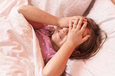 Sevimli İspanyol kız. Elleri yatakta uzanmış gözleri üzerinde stresli.