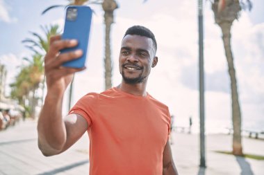 Young african american man smiling confident make selfie by the smartphone at street