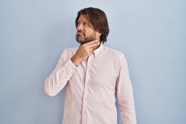 Zarif gömlek giyen yakışıklı orta yaşlı bir adam. Acı veren boynuna dokunuyor. Grip, mantar ve enfeksiyon yüzünden boğazı ağrıyor. 