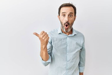 Orta yaşlı, sakallı, soyutlanmış arka planda dikilen İspanyol bir adam elleri yana dönük, ağzı açık, şaşkın bir ifadeyle şaşırdı.. 