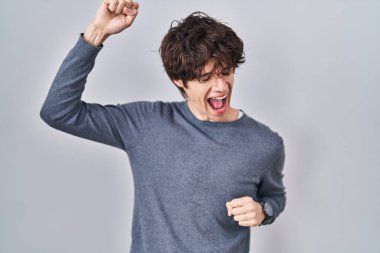 Young man standing over isolated background dancing happy and cheerful, smiling moving casual and confident listening to music 