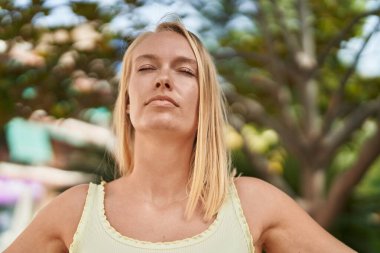 Young blonde woman breathing at park