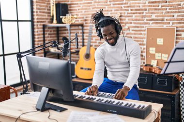 Müzik stüdyosunda piyano çalan Afrikalı Amerikalı kadın müzisyen.