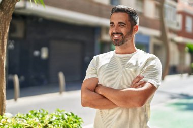 Genç İspanyol adam gülümsüyor. Kendine güveni tam. Sokakta çapraz hareketlerle duruyor.