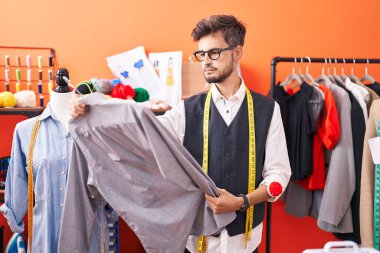 Atölyede terzi tişörtü tutuyor.