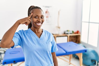 Saçları örgülü siyah bir kadın ağrı kesici kliniğinde çalışıyor. Gülümsüyor, tek parmağıyla işaret ediyor. Harika bir fikir ya da düşünce, iyi bir hafıza. 