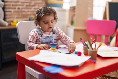 Anaokulundaki masada oturan sevimli İspanyol kız basketbol oynuyor.