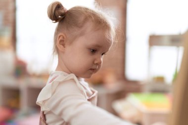 Anaokulunda rahat bir ifadeyle duran sevimli beyaz kız.