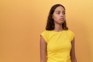 Young african american woman standing with sad expression over isolated yellow background