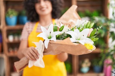 Young middle eastern woman florist holding bouquet of flowers at florist