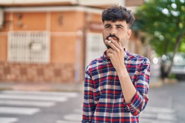 Young hispanic man smoking at street