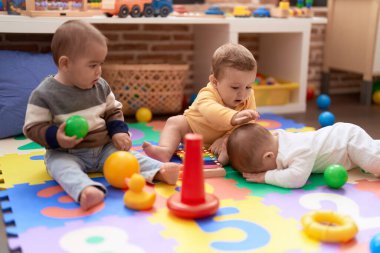 Anaokulunda yerde oturmuş oyuncaklarla oynayan bir grup çocuk.