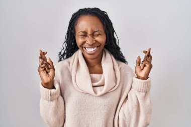 Beyaz arka planda duran Afrikalı kadın umut ve gözleriyle gülümseyerek işaret ediyor. Şans ve batıl inançlar. 