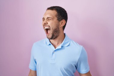 İspanyol adam pembe arka planda kızgın ve kızgın bağırıyor öfkeyle bağırıyor. öfke ve agresif konsept. 