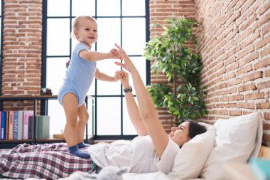 Anne ve oğlu yatakta uzanıp yatak odasında oynuyorlar.
