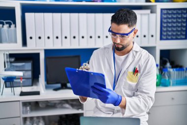 Genç Arap bilim adamı. Laboratuvarda çalışan panoya yazı yazıyor.