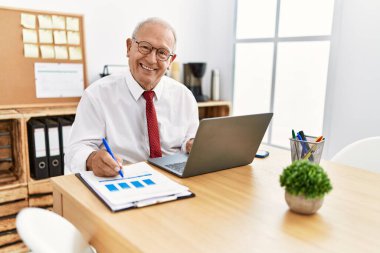 Üst düzey bir iş adamı ofiste çalışan bir belgeye yazıyor.